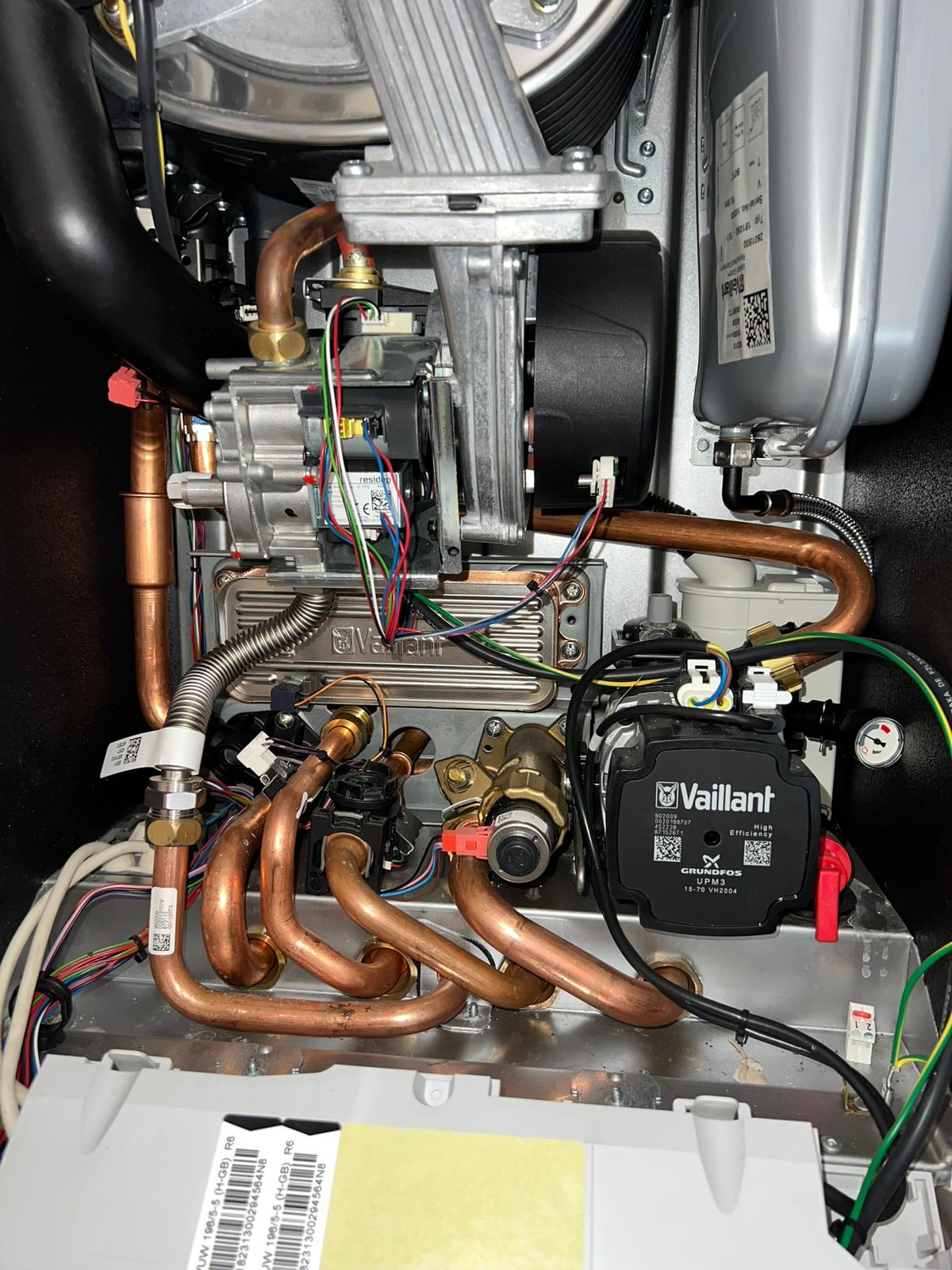 Internal view of a Vaillant combi boiler showing the gas valve, Grundfos pump and copper flow and return pipework during a central heating service