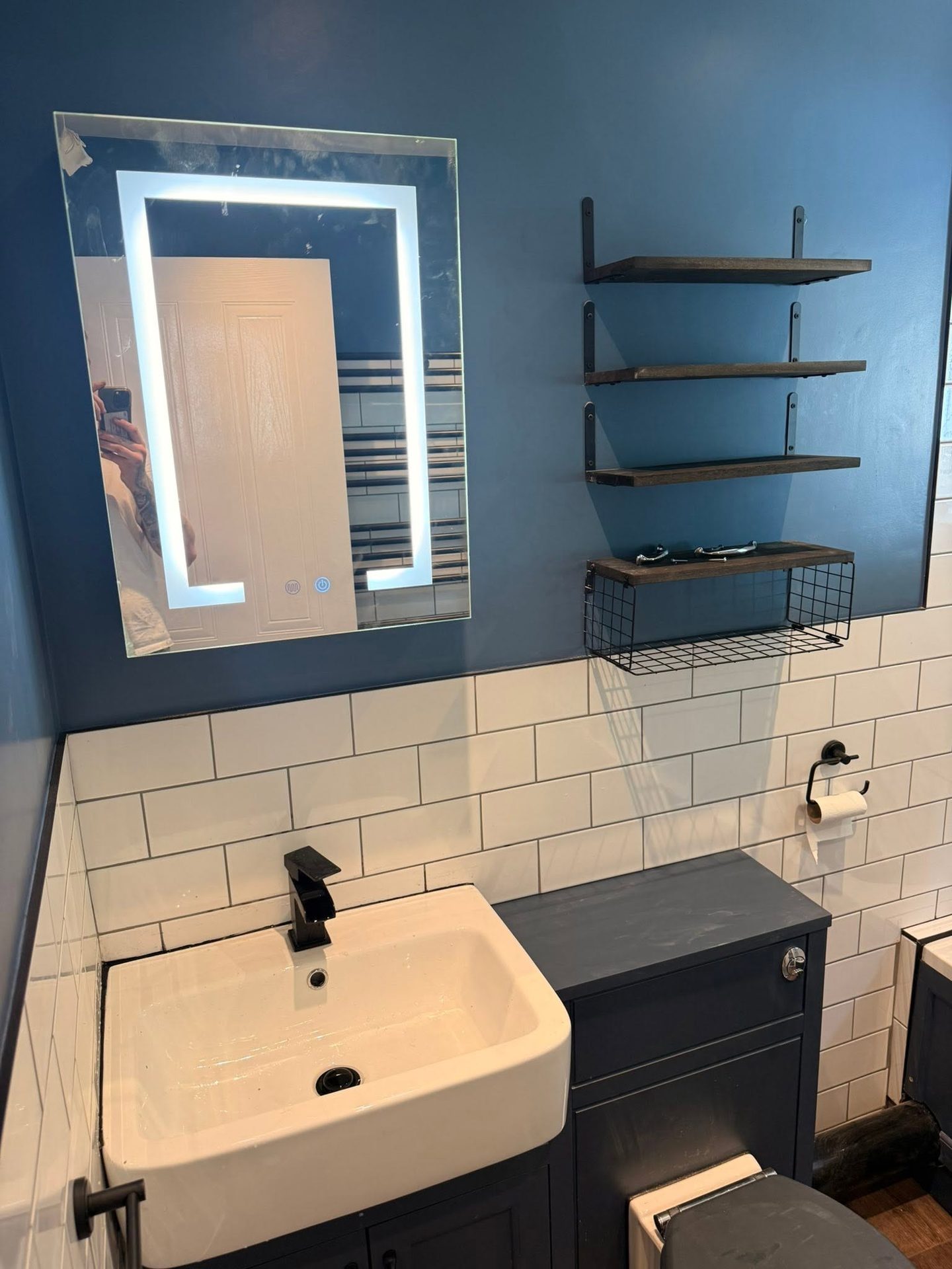 Square white countertop basin with a matt black mixer tap beneath a backlit bathroom mirror